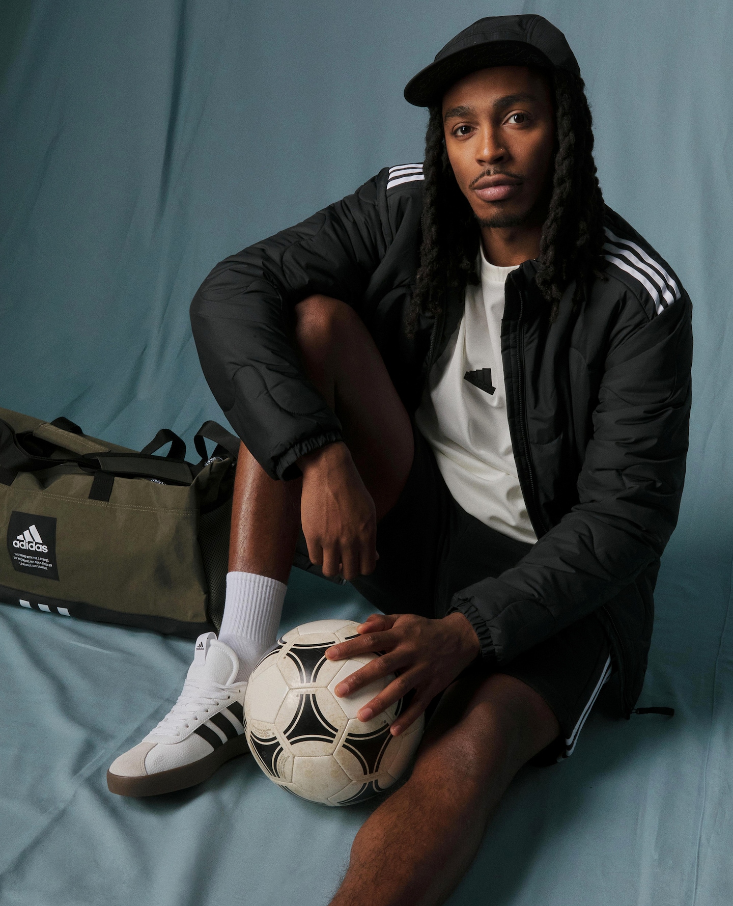 Man sat on the floor wearing a track suit top and cap