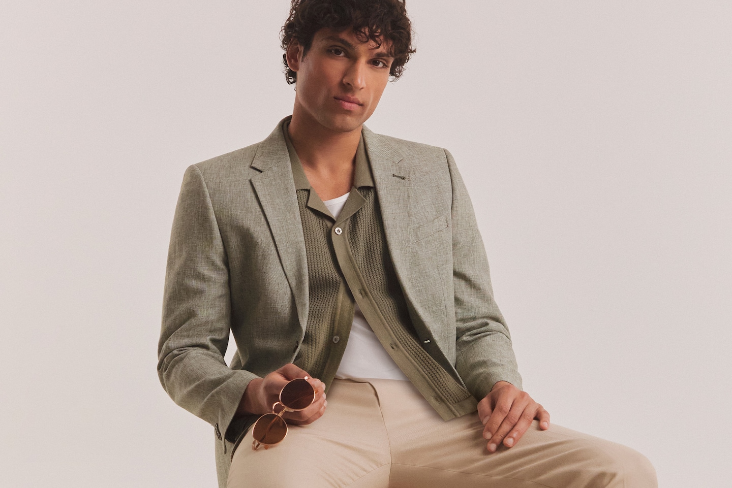 Model wearing khaki blazer and green sweater