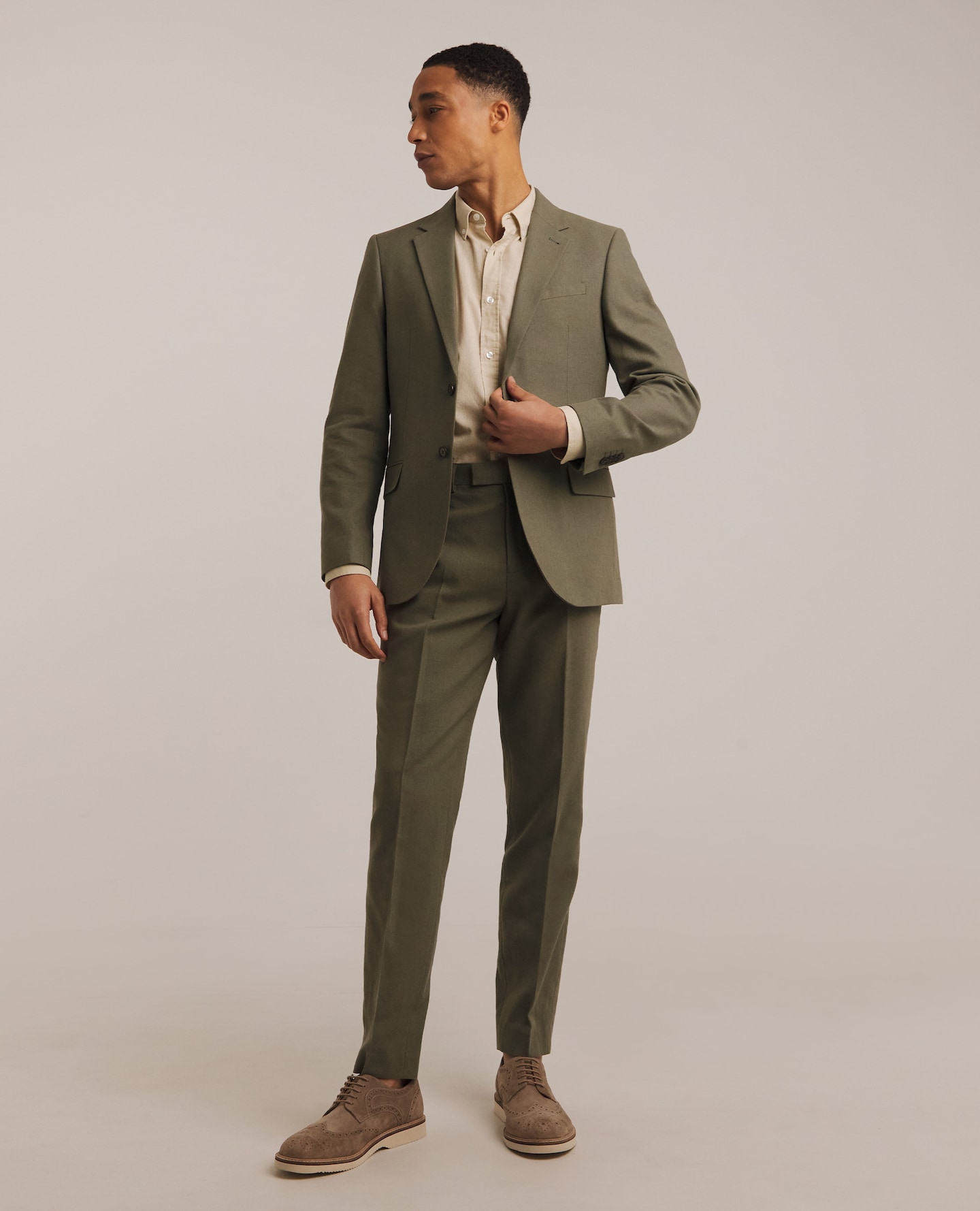 Model wearing green suit and cream shirt