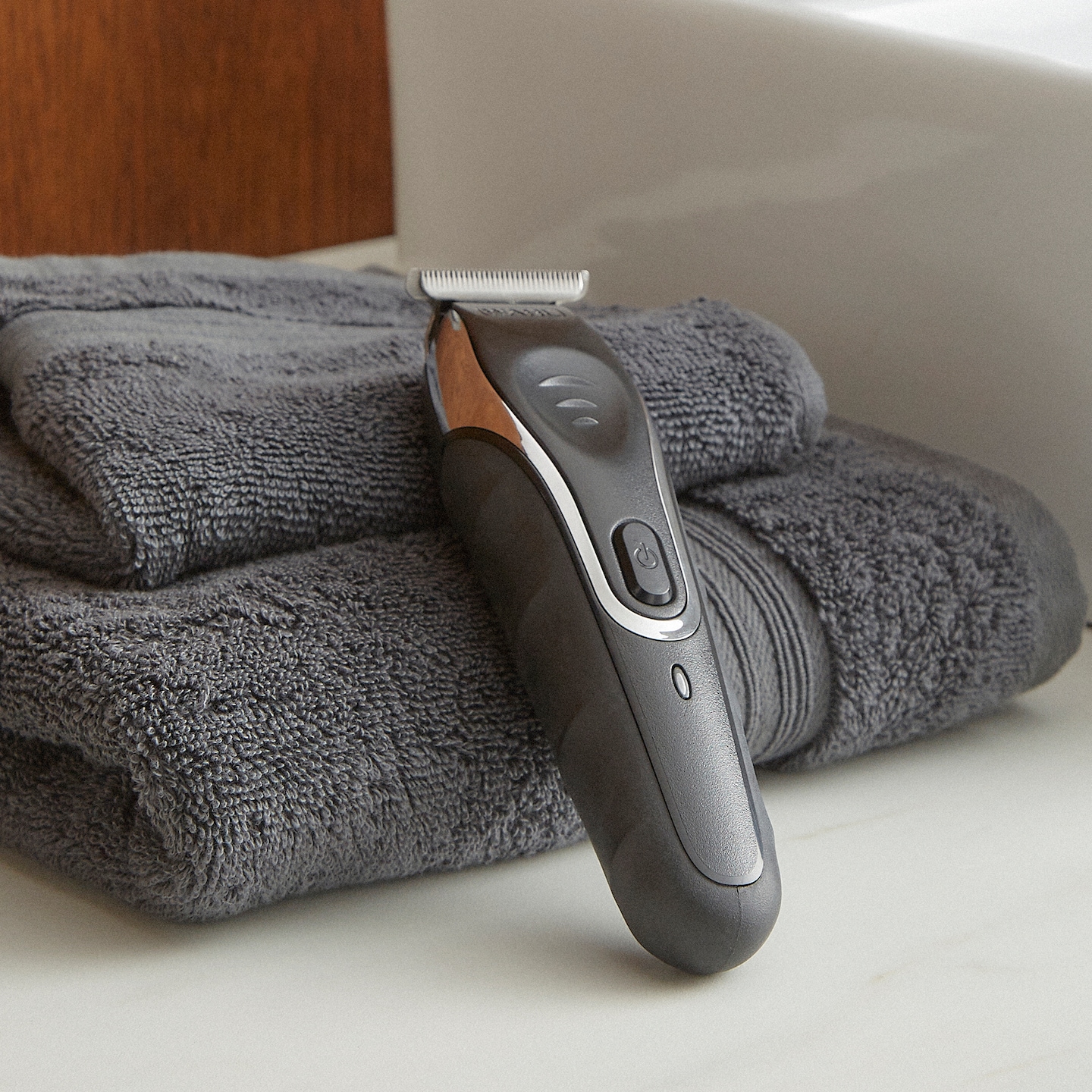 Grey hair clipper resting against a pile of towels
