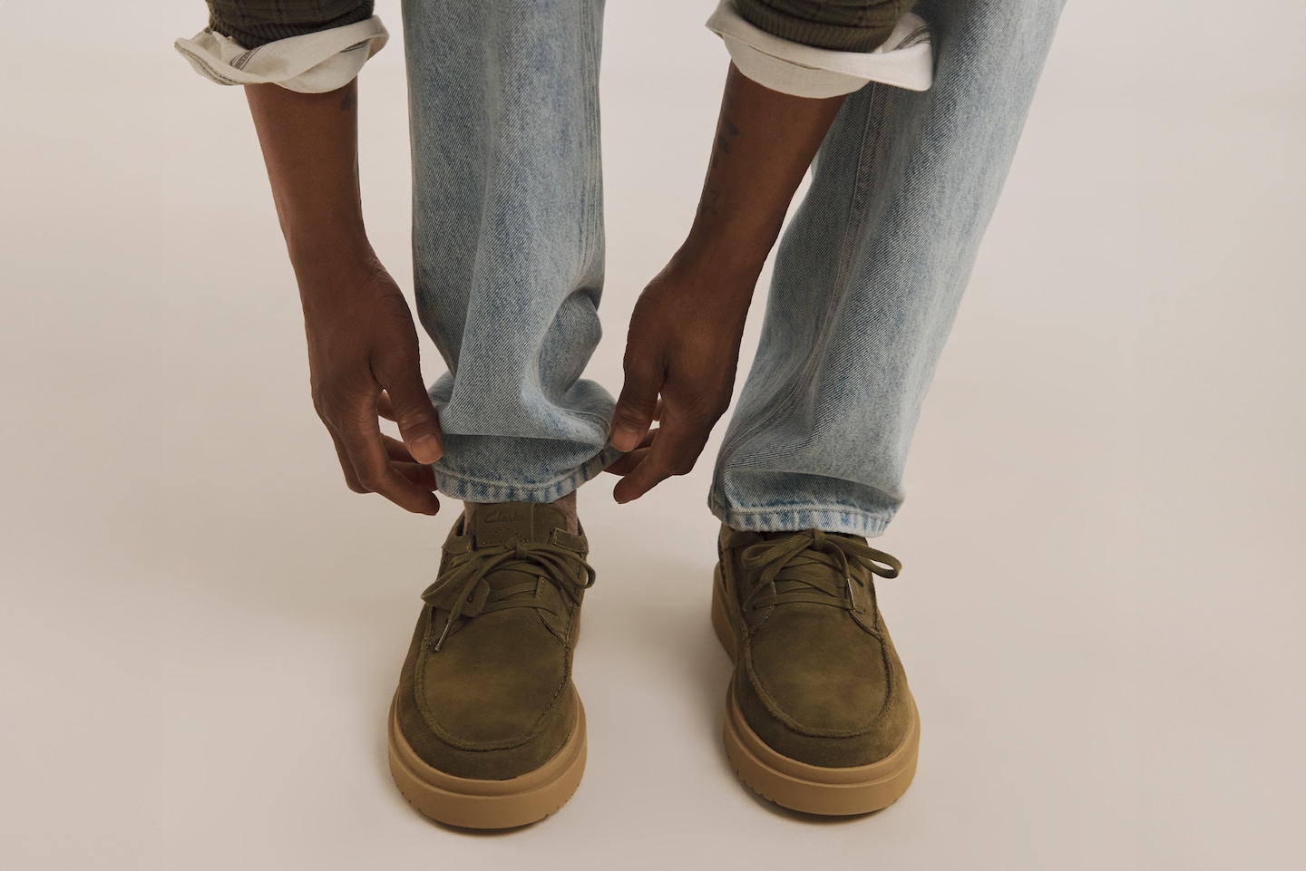 Model adjusting a pair of khaki loafers