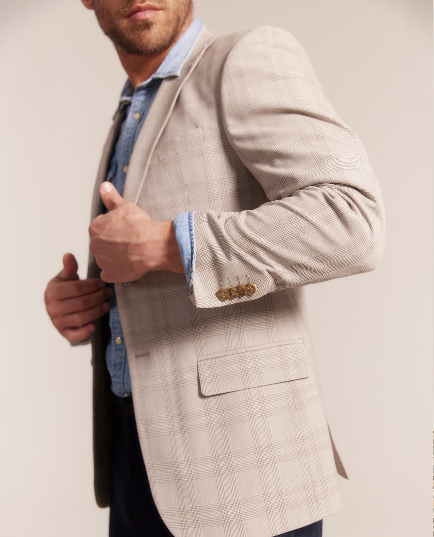 Model wears smart beige blazer and blue shirt