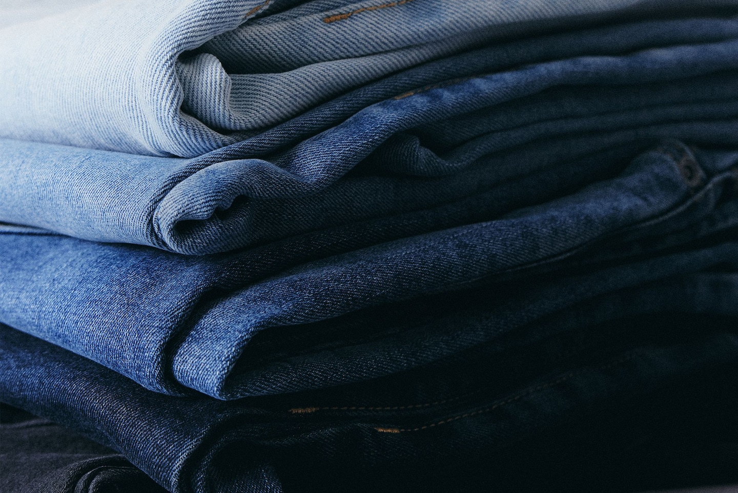 Jeans in a pile, various washes. Men's Jeans Decoded.