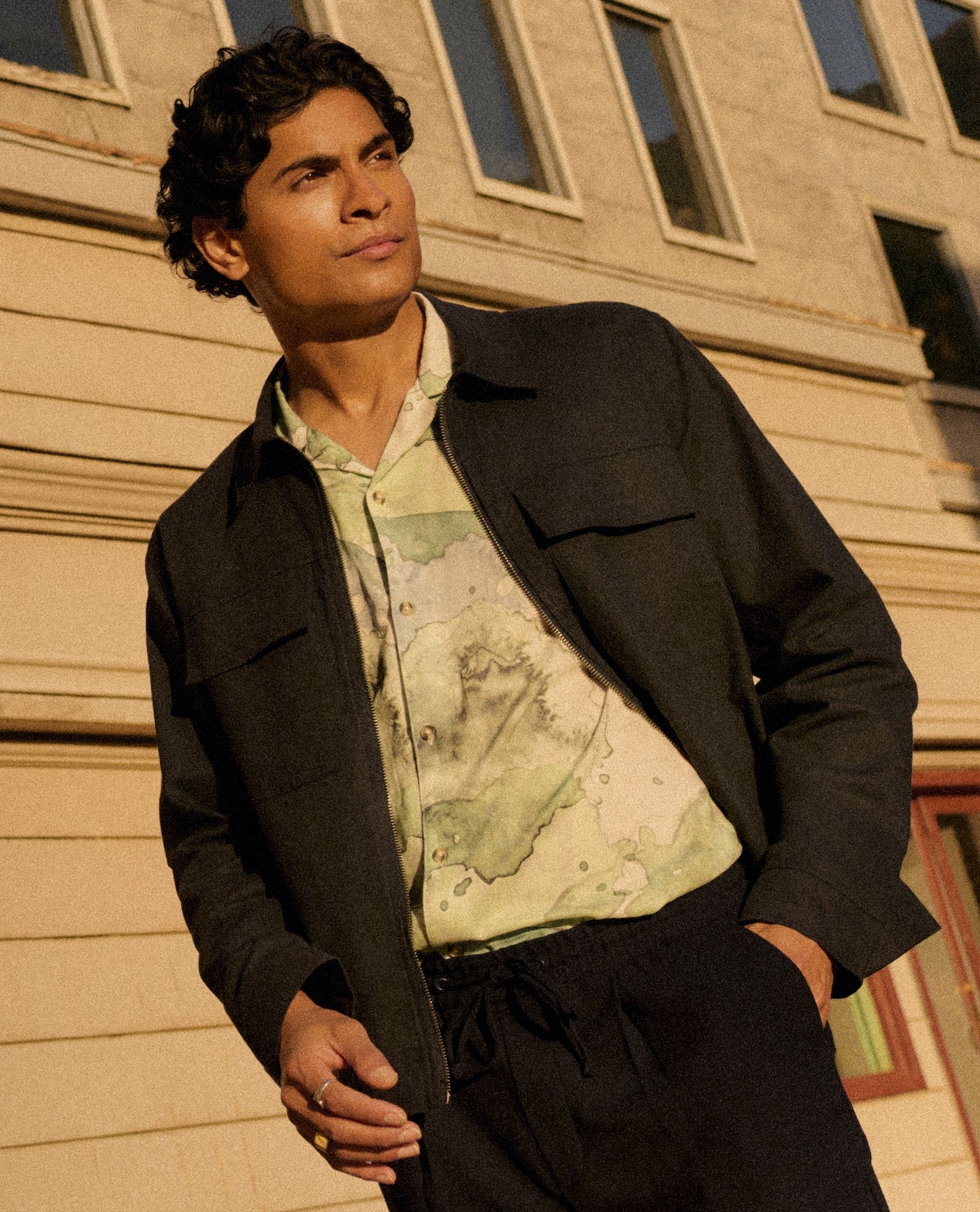 Guy wearing a light jacket on a sun soaked street