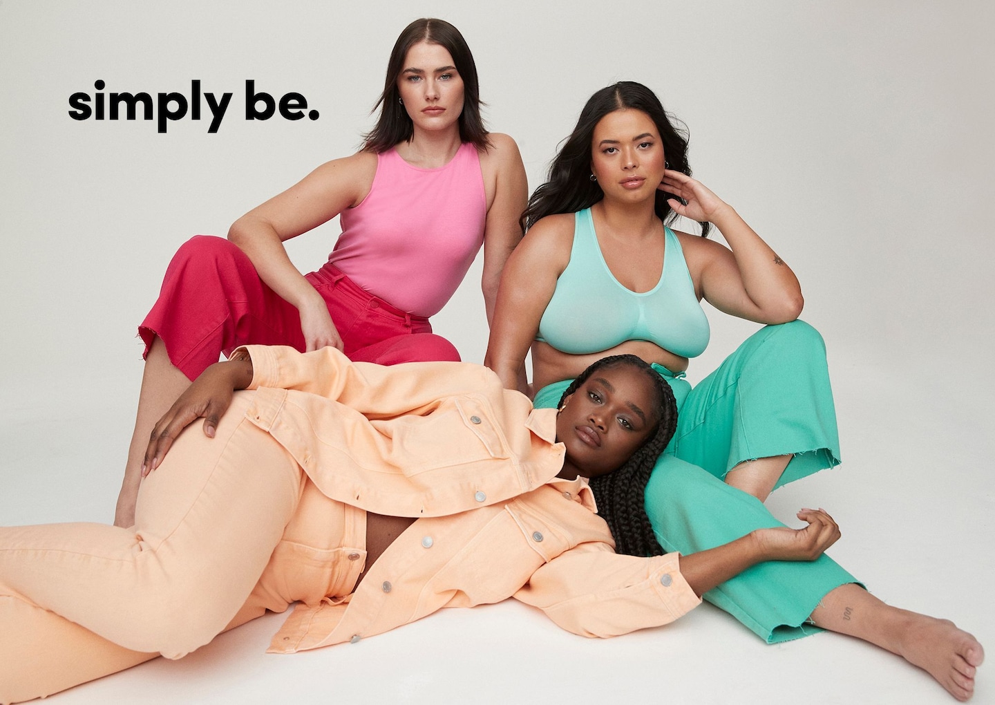 3 women sat on the floor wearing colourful outfits