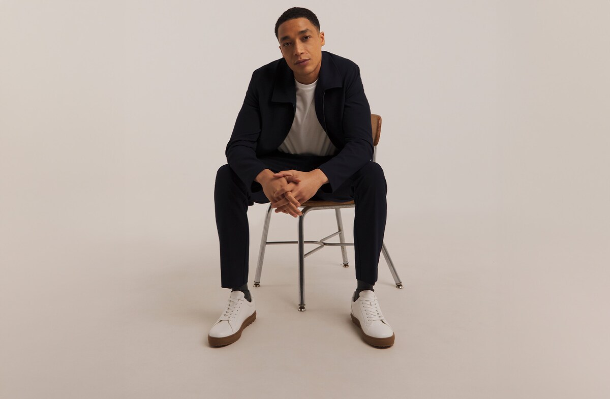Model sat on chair wearing black jeans and black jacket
