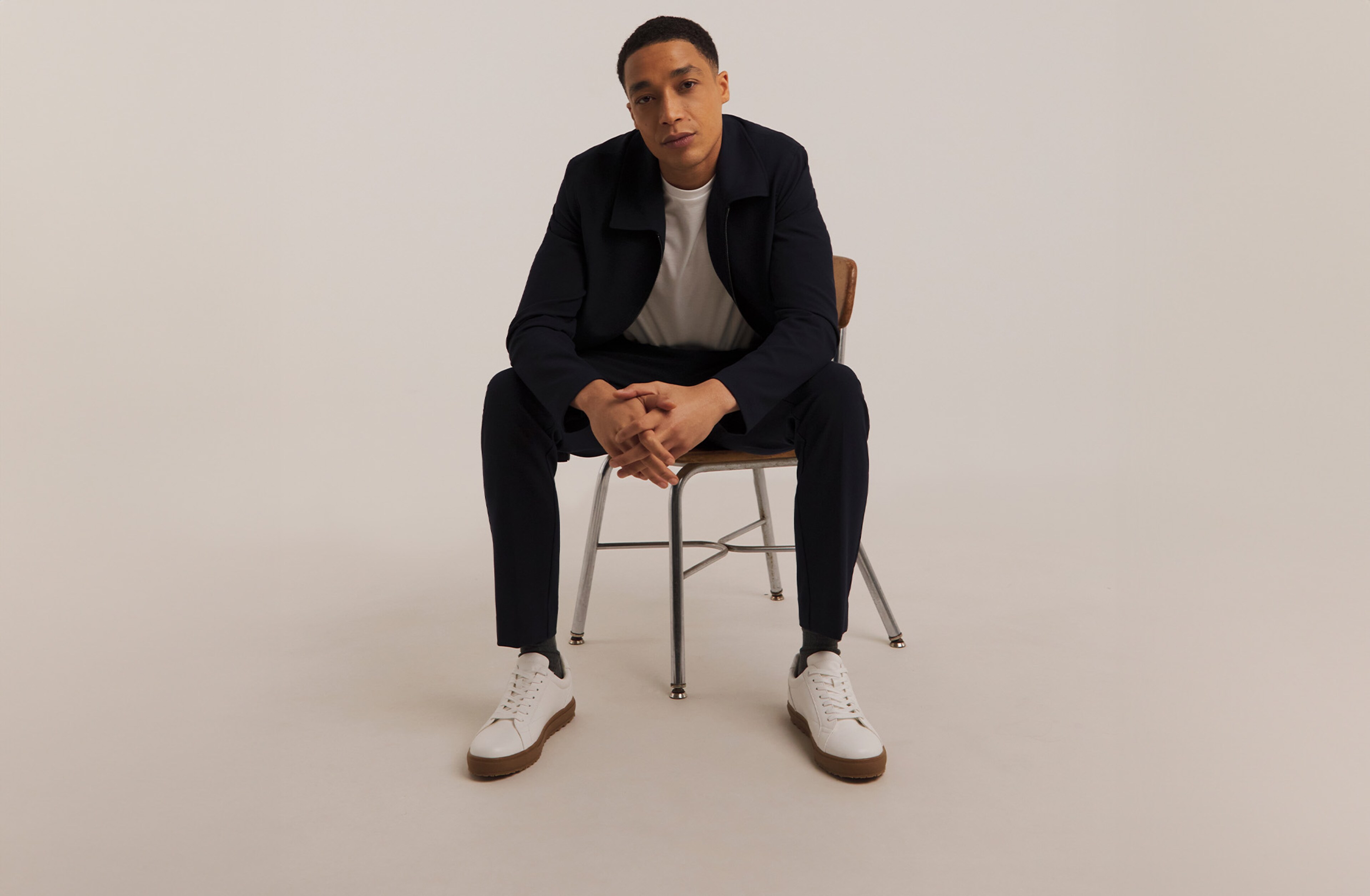 Model sat on chair wearing black jeans and black jacket