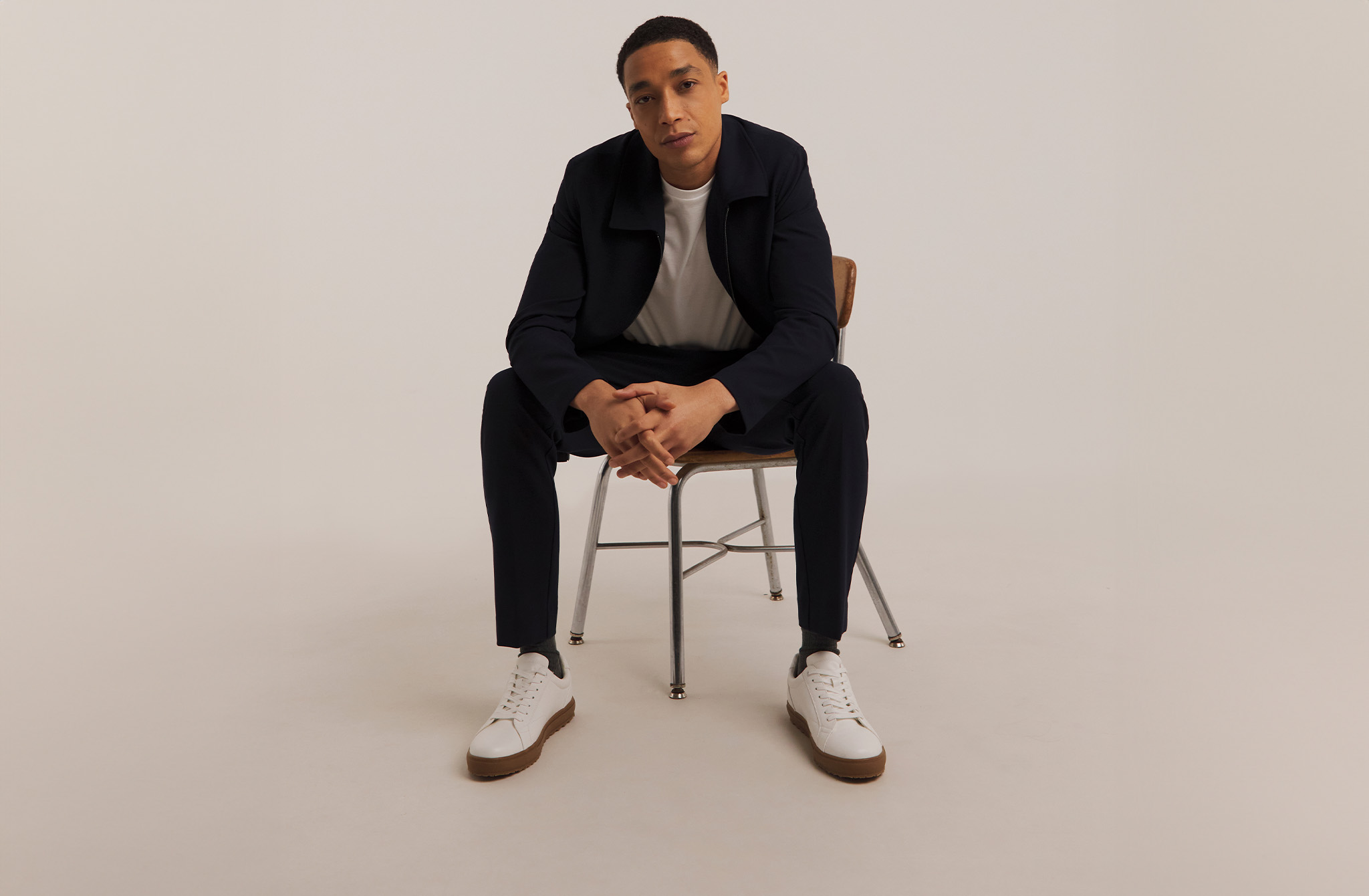 Model sat on chair wearing black jeans and black jacket