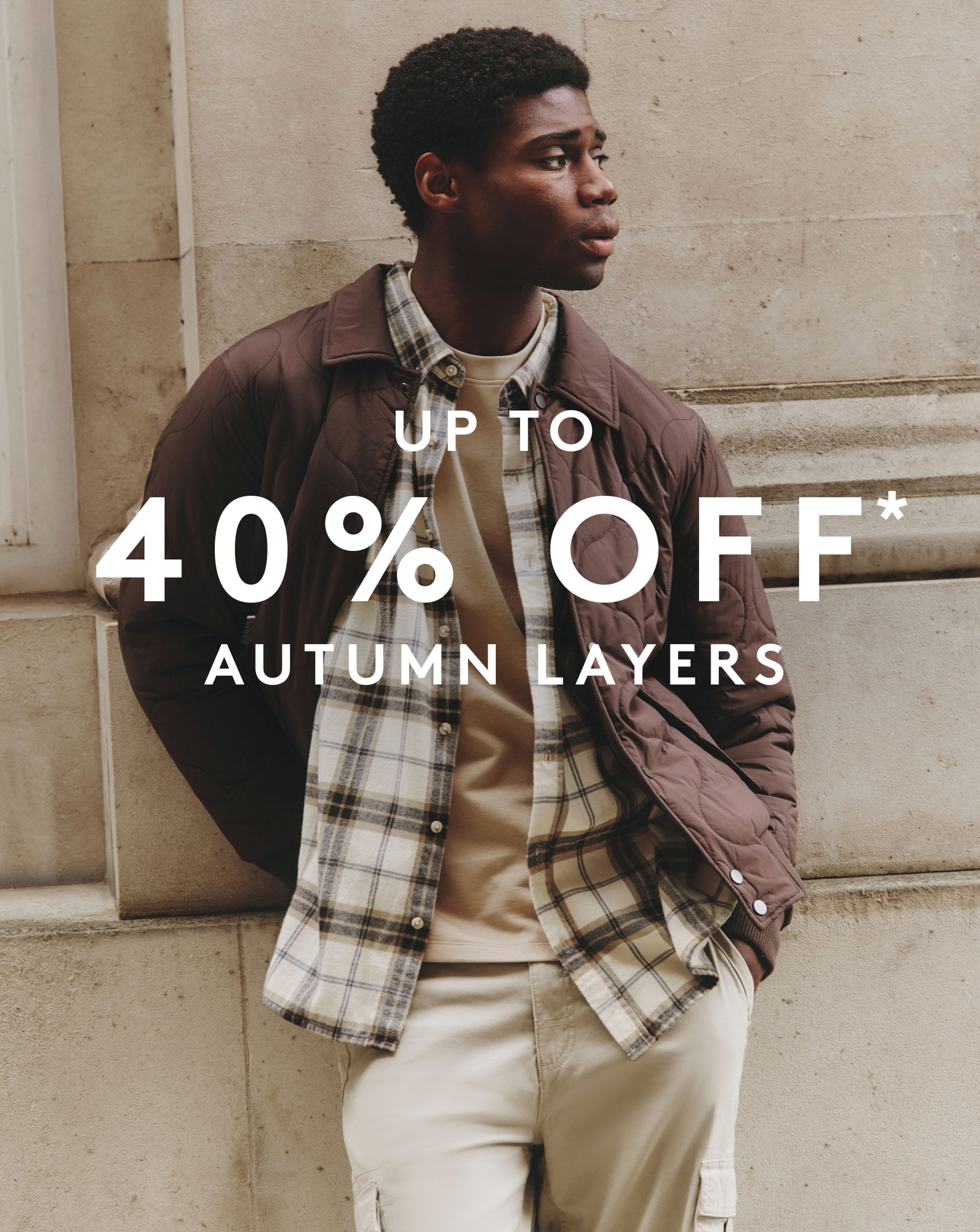 Model wearing autumnal layers that include a chequered shirt and a brown jacket