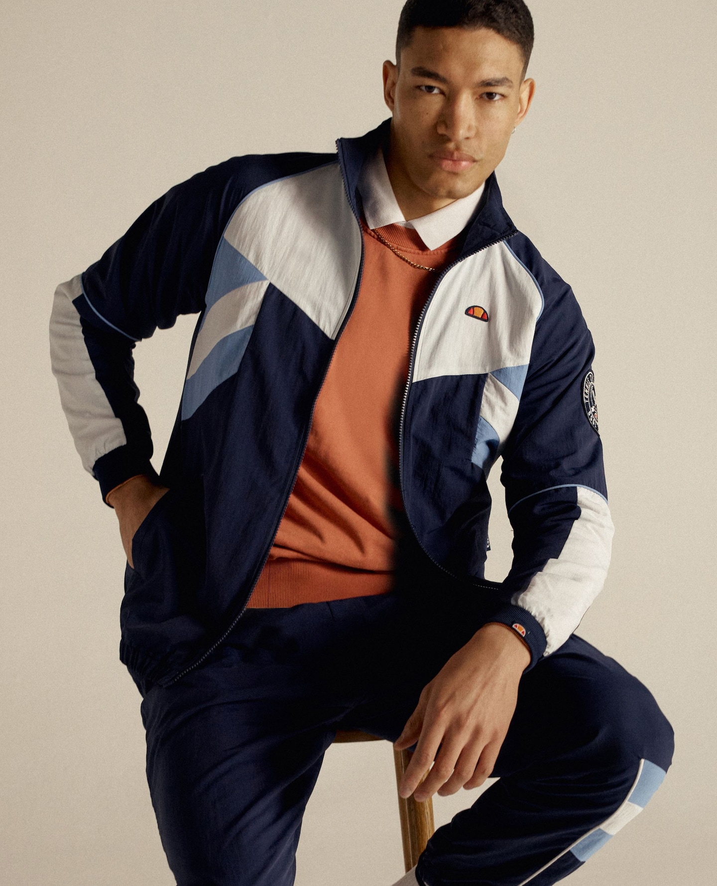 A man wearing a black and grey tracksuit top with a polo shirt