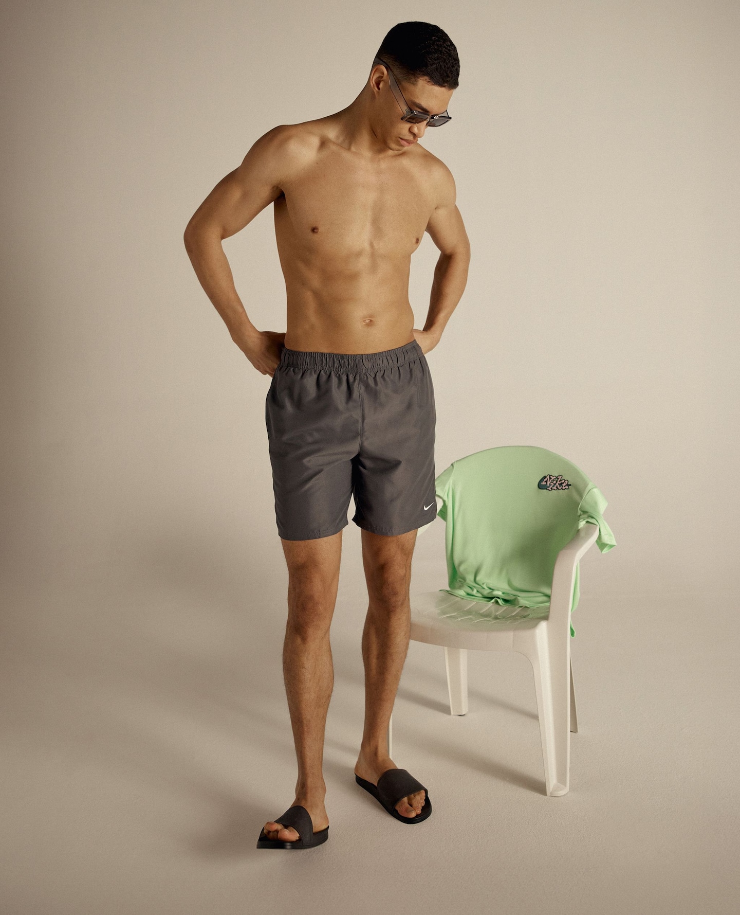 Model wears Nike swim shorts and Nike green swim top displayed