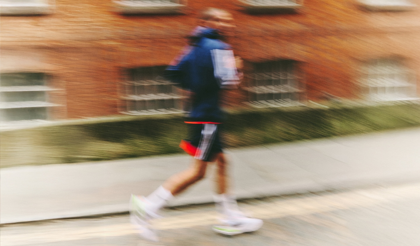 Runner in motion pictured against backdrop of suburban town houses wears adidas running gear