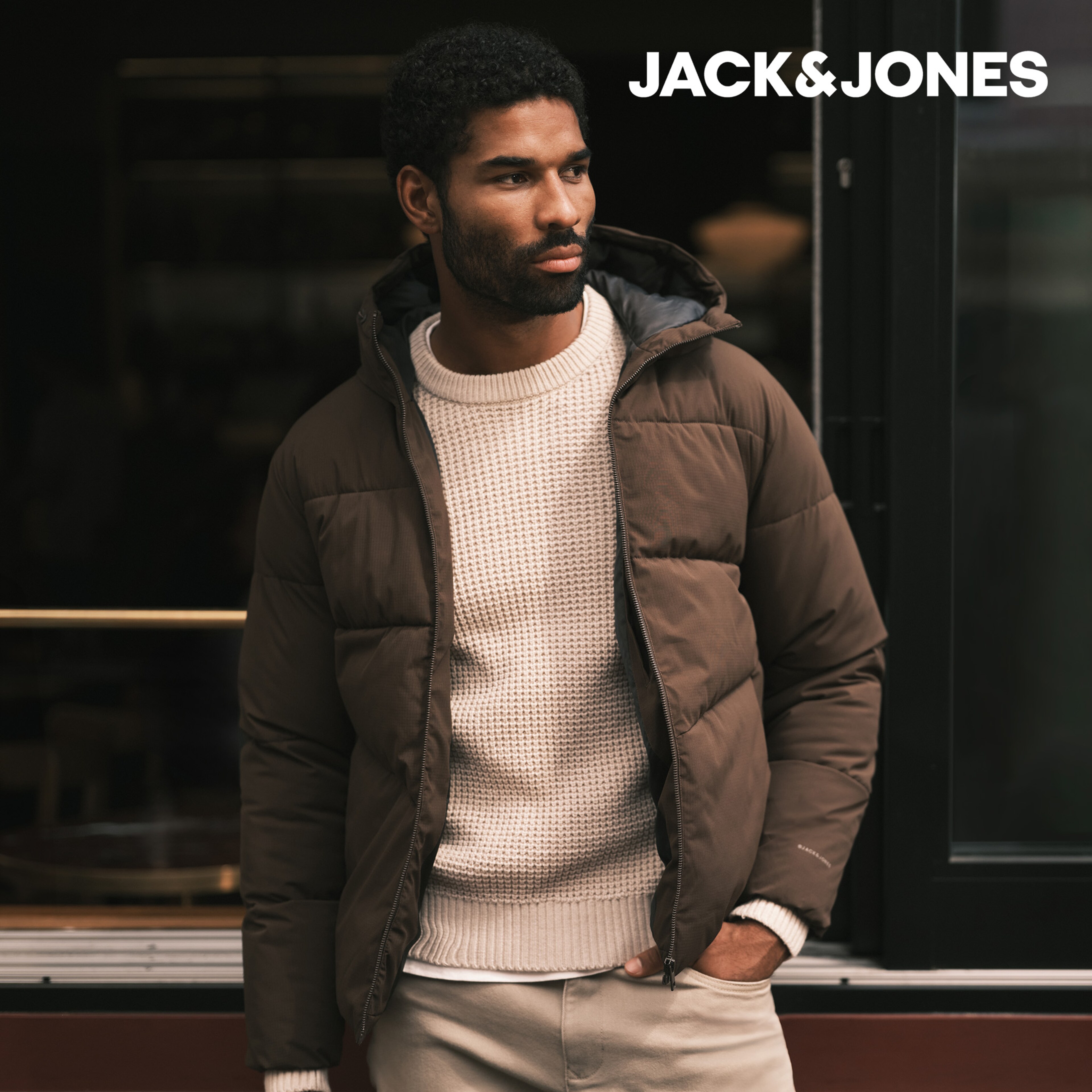 Model wearing a cream knitted jumper with a khaki Jack & Jones puffer jacket