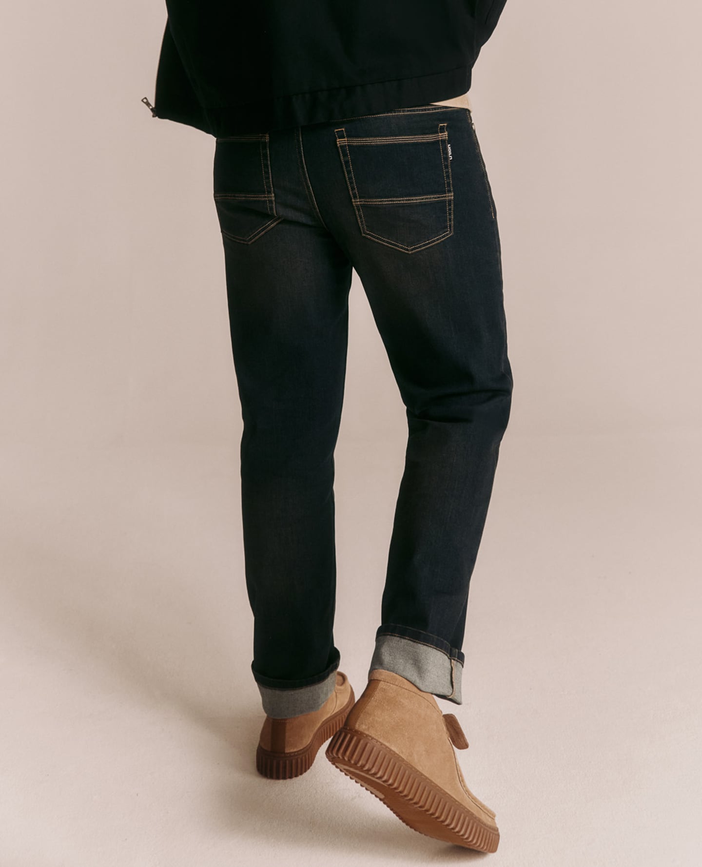 Model wears dark jeans. Slim Fit is depicted.
