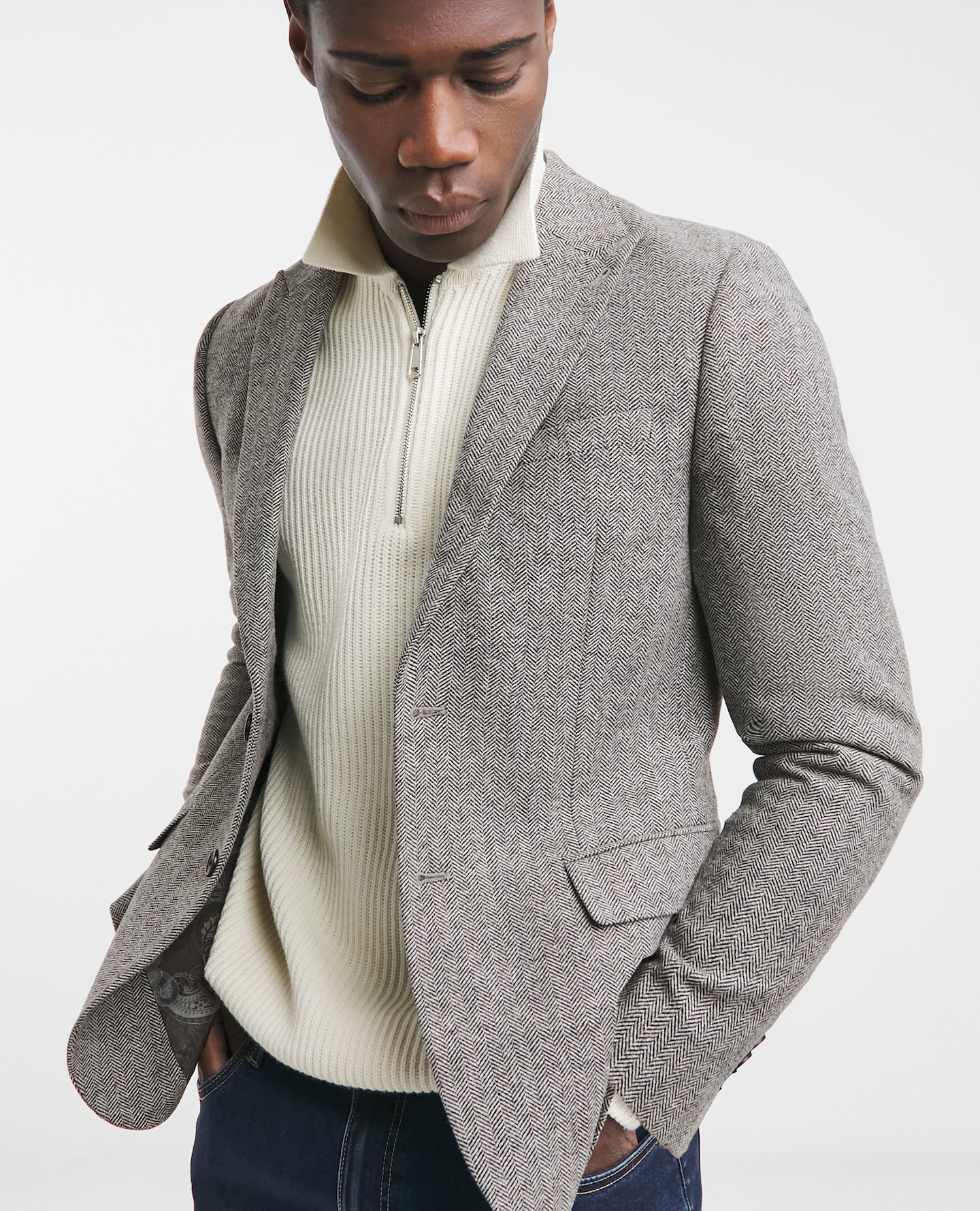 Model wearing grey blazer with white zip up sweater
