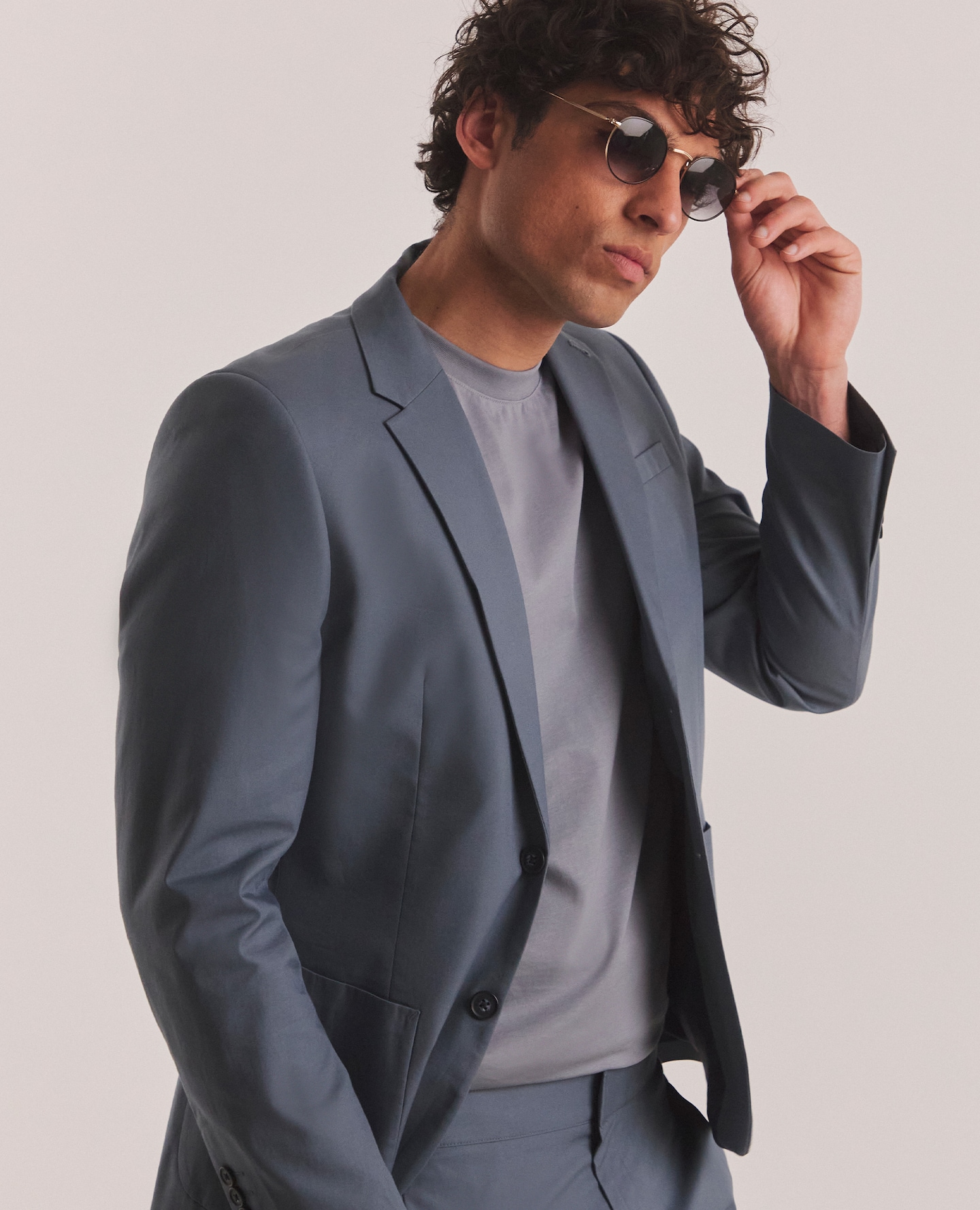 Model wearing blue suit, blue t-shirt and sunglasses
